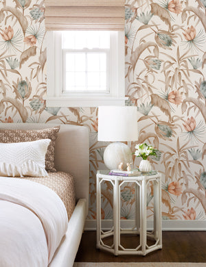 Natural-toned Tropical Wallpaper by Rylee + Cru is in a bedroom with a linen framed bed and a glass hexagonal nightstand