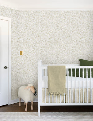 The sommerville natural wallpaper is in a children's room with a sheep toy and a white crib with ivory and blue linens