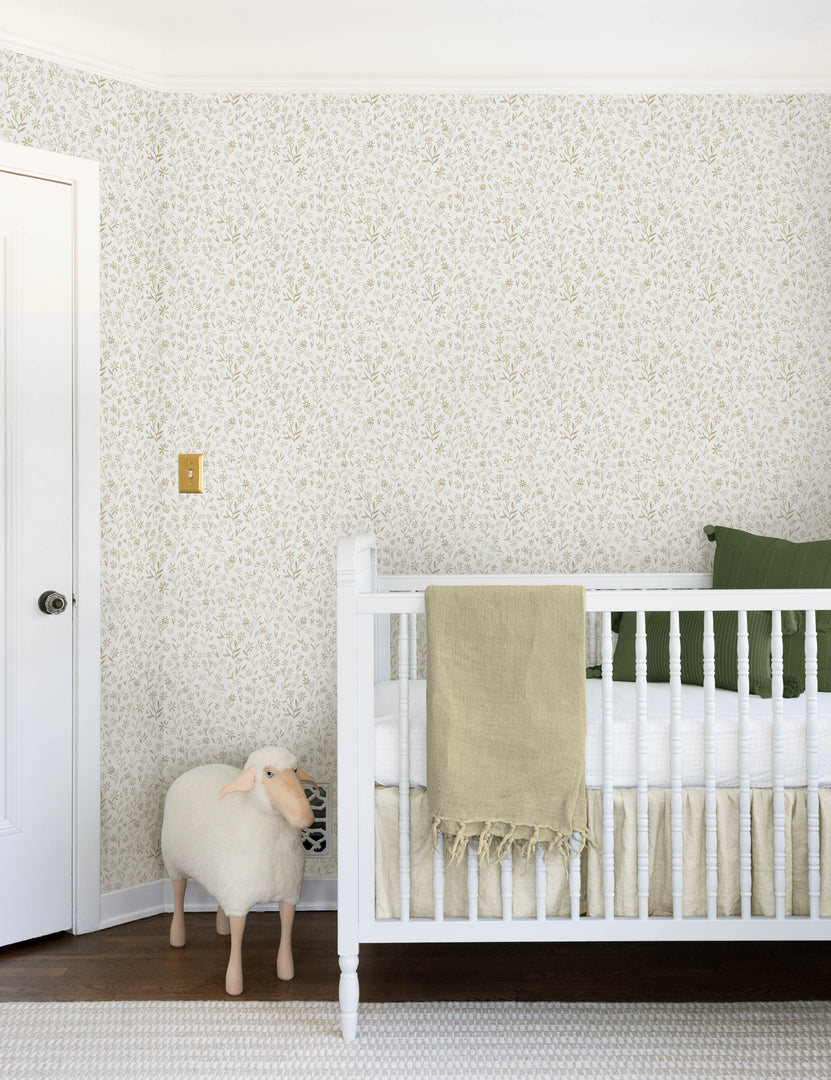 #color::natural | The sommerville natural wallpaper is in a children's room with a sheep toy and a white crib with ivory and blue linens