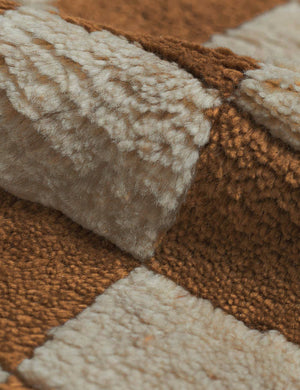 Detailed view of the high-low pile fiber and texture on the Irregular ochre checkerboard rug by Sarah Sherman Samuel