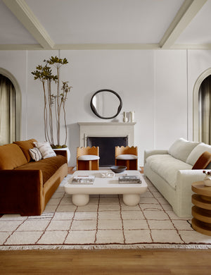 The Clouded square white coffee table sits between a cognac velvet and ivory linen sofas on a ochre and ivory colored rug