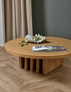 Pentwater natural wooden Round Coffee Table with a white ribbed decorative bowl and magazine sitting atop it