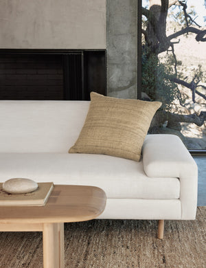 Jonas natural-toned Silk Pillow sits on a white sofa in a living room with a jute rug and an oval wooden coffee table