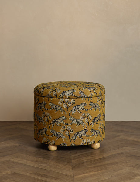 #color::tiger-gold-by-sarah-sherman-samuel #size::24-dia | Kamila tiger golden round 24 inch ottoman with storage space and pinewood feet by Sarah Sherman Samuel sits in a studio room
