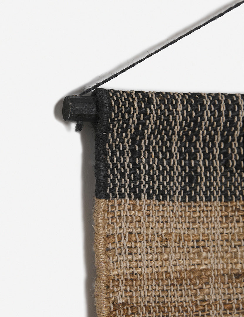 | Close-up of the hanging pole on the top of the Katlee black and natural flat weave Wall Hanging
