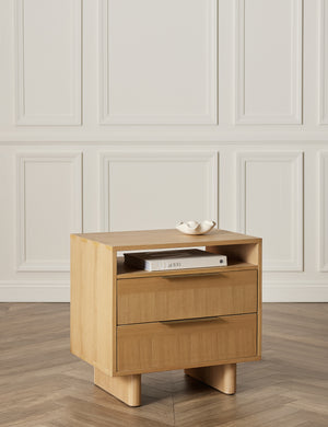 The Hillard white oak veneer nightstand sits in a studio room with chevron floors and white accented walls