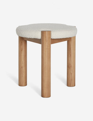 Kittredge compact stool with a natural wooden three-legged silhouette and cream boucle cushioning