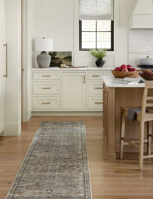 Amalia distressed traditional rug in its runner size lays in a kitchen with white cabinetry and marble countertops