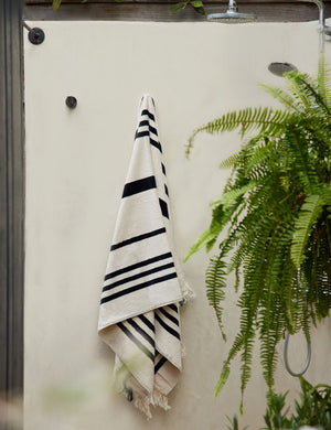 Black and white striped Beach Towel by Business & Pleasure Co hangs from an outdoor shower space
