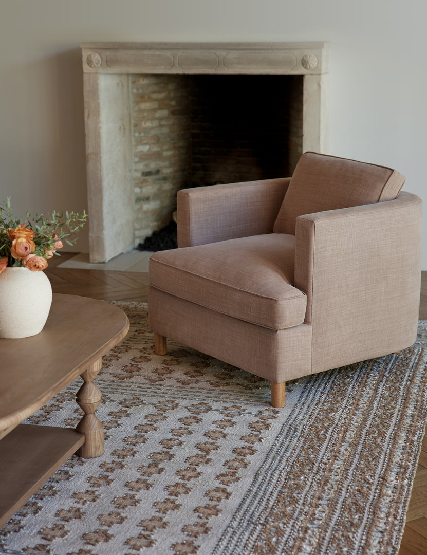 #color::apricot-linen | The Belmont apricot linen accent chair sits atop a gray and neutral-toned rug in front of a wooden framed fireplace 