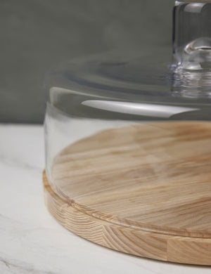 Close-up of the left half of the Lotta cheese and pastries glass dome with ash wood base by LSA International