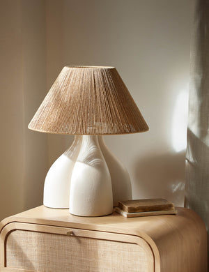 Gustav woven shade sculptural table lamp styled on a light wood cane front nightstand.