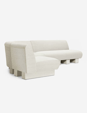 Angled view of the Lena left-facing natural linen sectional sofa with upholstered beam legs.