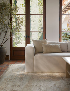 The victor natural pillow in both sizes sit together on a natural linen sofa in front of a black-framed window