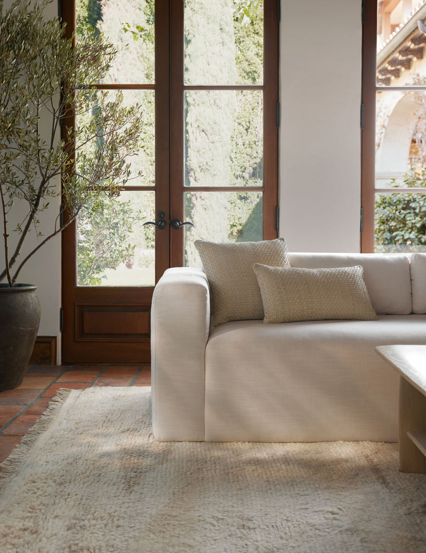#color::natural #style::square #style::lumbar | The victor natural pillow in both sizes sit together on a natural linen sofa in front of a black-framed window