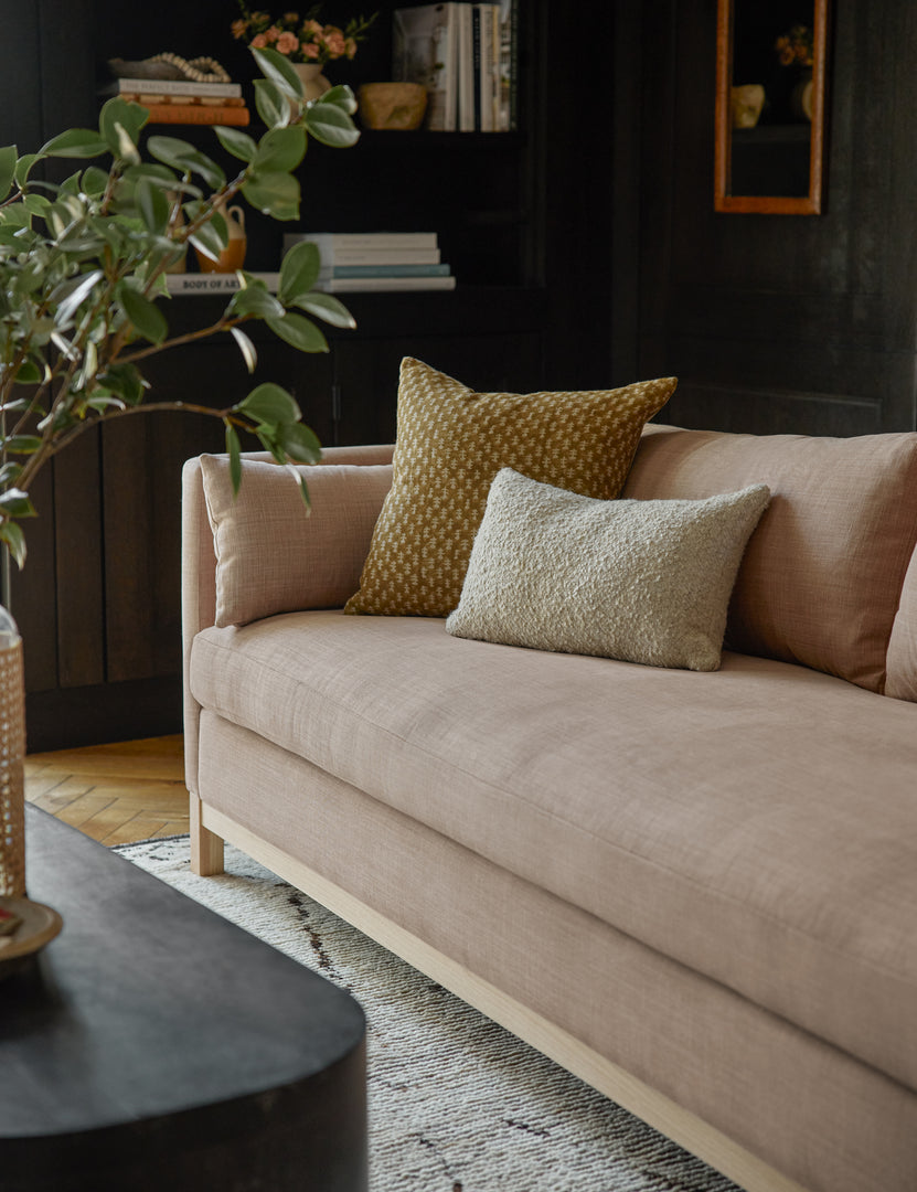 #size::84-W #size::96-W #color::apricot-linen | Apricot Linen Hollingworth Sofa sits in a living room with black walls, a gray boucle throw pillow, and an earth toned throw pillow