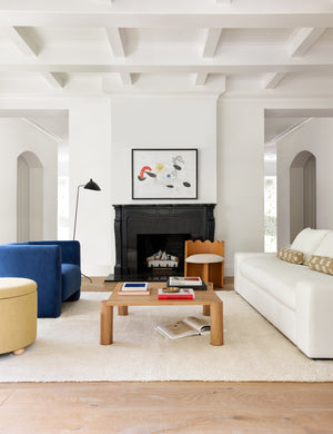 The Noa Moroccan Shag Rug sits under a blue velvet accent chair, a square wooden coffee table, and a white linen sofa