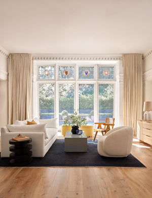 The Heritage indigo rug lays in a living room with stained glass windows under a striped coffee table and a white sofa