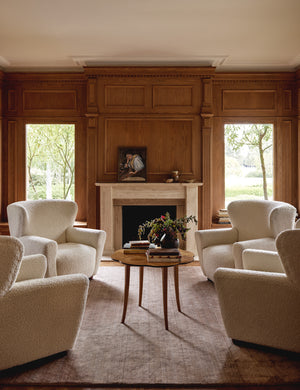 The Chiltern mauve rug lays in a living room with wooden accented walls under four boucle accent chairs