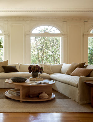 The Portola Mushroom natural linen Slipcover corner sectional Sofa sits in a room with a round coffee table and accented walls