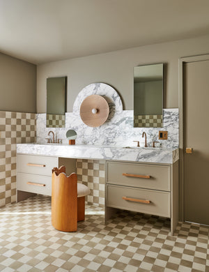 Ripple Accent Chair sits in a bathroom in between two sinks with a marble counter top and checker-tiled floors and walls