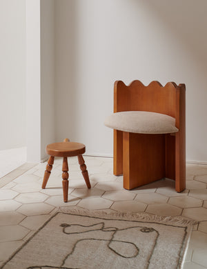 The Line Drawing Flatweave Rug lays on a hexagonal tile floor with a ripple-back chair and a small wooden stool