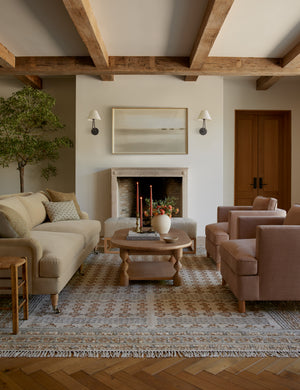 The Keziah slate rug lays in a living room under a beige velvet, an oval coffee table, and two accent chairs