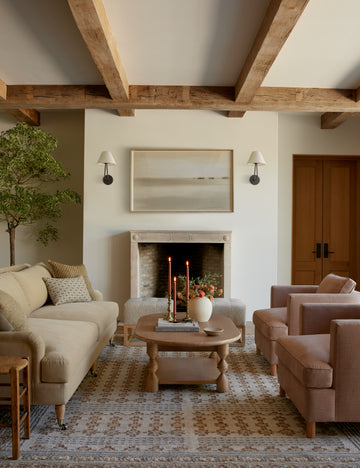 #showall::39867235795043 | Two Hayden double-armed black sconce lights hang on both sides of a landscape painting in a living room with warm-toned furniture