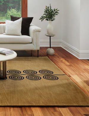 The Laci natural rug lays in a living room under a round coffee table, a stone side table, and an ivory sofa