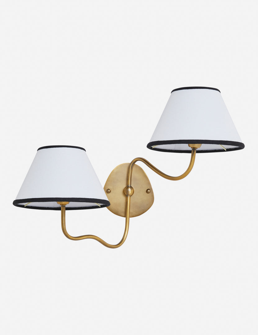 #color::black-trim #finish::brass | Magdalene brass double sconce with a white linen shade that has a black trim, a round wall mount, and an arched arm