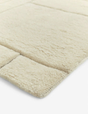 The corner of the Maleena cream hand-knotted wool and cotton area rug with abstract line tufting