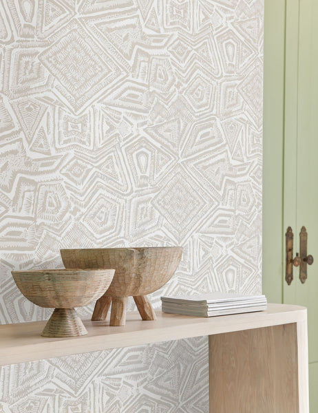 | The Malou gray geometric Wallpaper by Malene Barnett sits in a room with green french doors, two wooden centerpiece bowls, and a wooden side table