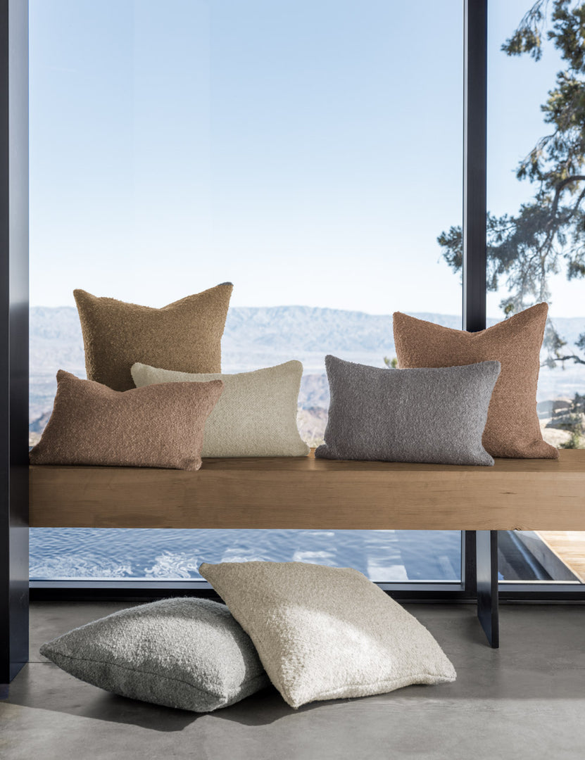 #color::terracotta #size::20--x-20- | Manon linen boucle pillows sit on a wooden bench in front of floor to ceiling windows with a view of the ocean