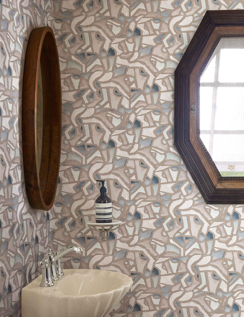 | The mosaic wallpaper is in a bathroom with a scalloped sink, a wood framed mirror, and an octogonal window