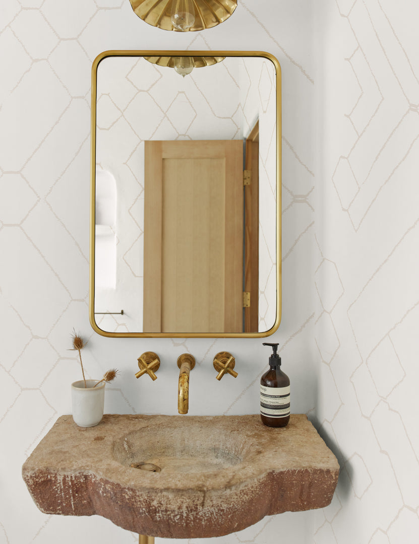 #color::natural | The Moroccan beige and ivory Wallpaper Mural by Sarah Sherman Samuel is in a bathroom with a wooden sink and a rectangular golden framed mirror with rounded edges.
