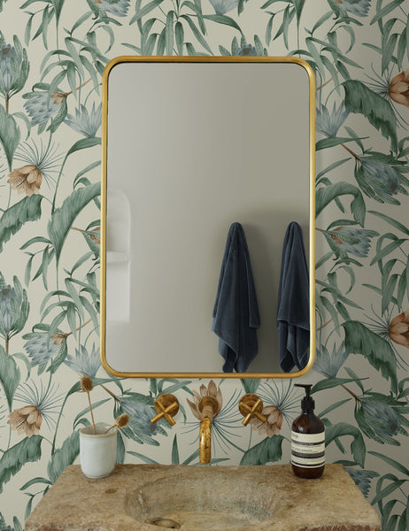 #color::green | Green-toned Tropical Wallpaper by Rylee + Cru is in a bathroom with a rounded gold mirror and a stone sink with gold hardware