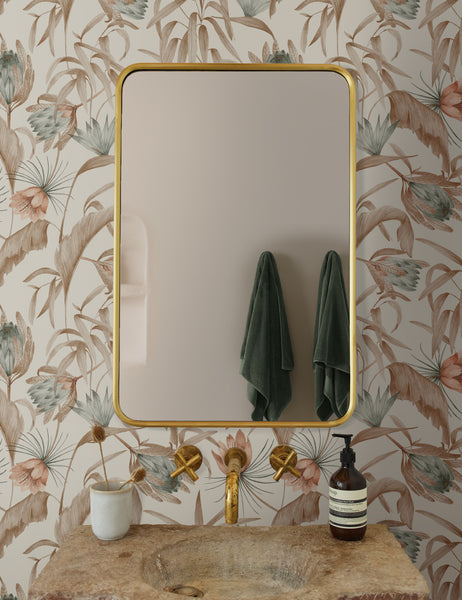 #color::natural | Natural-toned Tropical Wallpaper by Rylee + Cru is in a bathroom with a rounded gold mirror and a stone sink with gold hardware