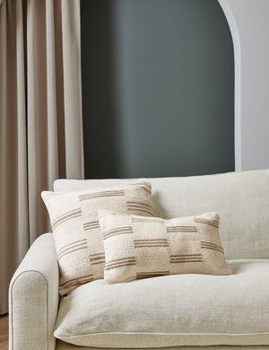 Two Stripe break natural and cream pillows by Sarah Sherman Samuel sit together atop a natural linen sofa in a room with green painted walls