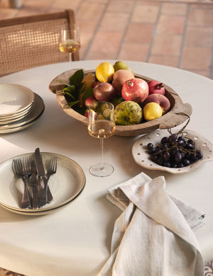 The set of six sand-toned stoneware nature dinner plates by thomas for rosenthal sit atop a dining room table with silverware, a long-stemmed wine glass, and a wooden centerpiece bowl