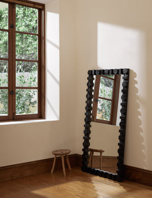 Sorenson full length wood framed floor mirror in black learning against a wall.