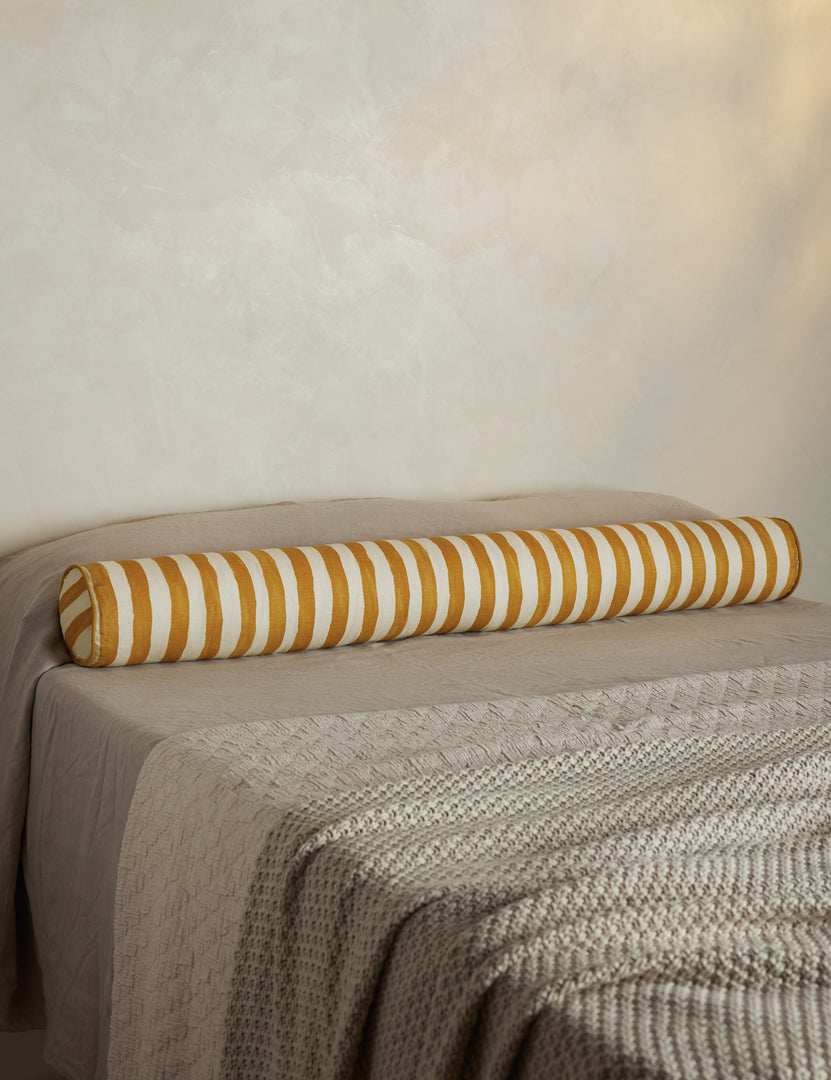 #color::goldenrod-and-ivory | Painterly stripe linen long bolster throw pillow in goldenrod and ivory styled on a bed