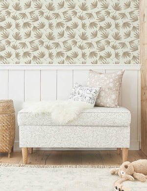 The palms wallpaper is in a kids room with a speckled linen bench, a fringed ivory rug, and a stuffed animal