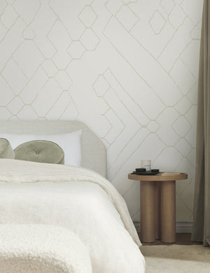 The Moroccan beige and ivory Wallpaper Mural by Sarah Sherman Samuel is in a bedroom with a talc linen bed, sage green velvet disc throw pillows, and a wooden nightstand with a sculptural base.