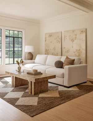 The Palau brown rug lays in a living room under a burl wood coffee table and a white sofa