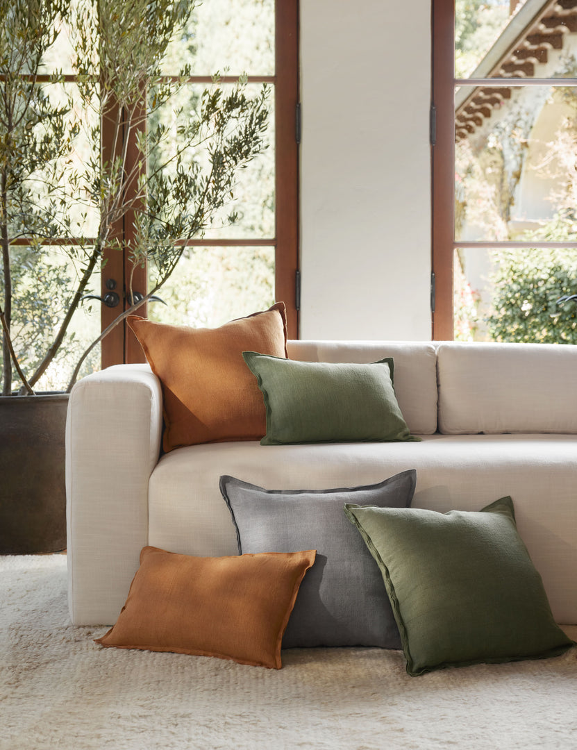 #color::dusty-blue #color::burnt-orange  #color::olive | The dusty blue, burnt orange, and olive arlo linen pillows sit together on a plush ivory rug and a natural linen sofa