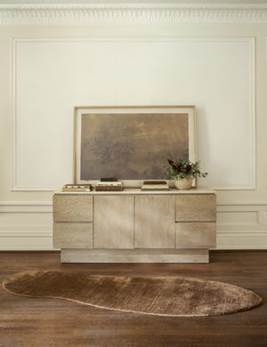 The longer Rangely Rug lays in front of a white-washed wooden sideboard with a large painting sitting atop it