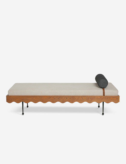 | Rise daybed with a cream upholstered cushion, scalloped wood detailing, and spindle legs by Sarah Sherman Samuel