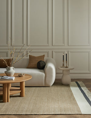The Rory rug lays in a living room under an ivory sofa, a round coffee table, and a white side table