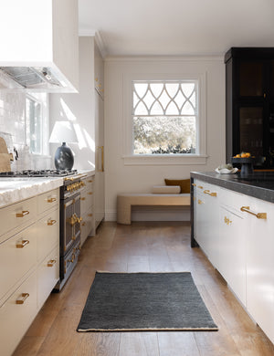 The Heritage indigo runner rug lays in a kitchen with white cabinetry, gold hardware, and marble countertops
