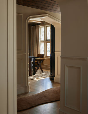 The longer Rangely Rug lays in a hallway that leads into a dining room with velvet dining chairs and a jute rug
